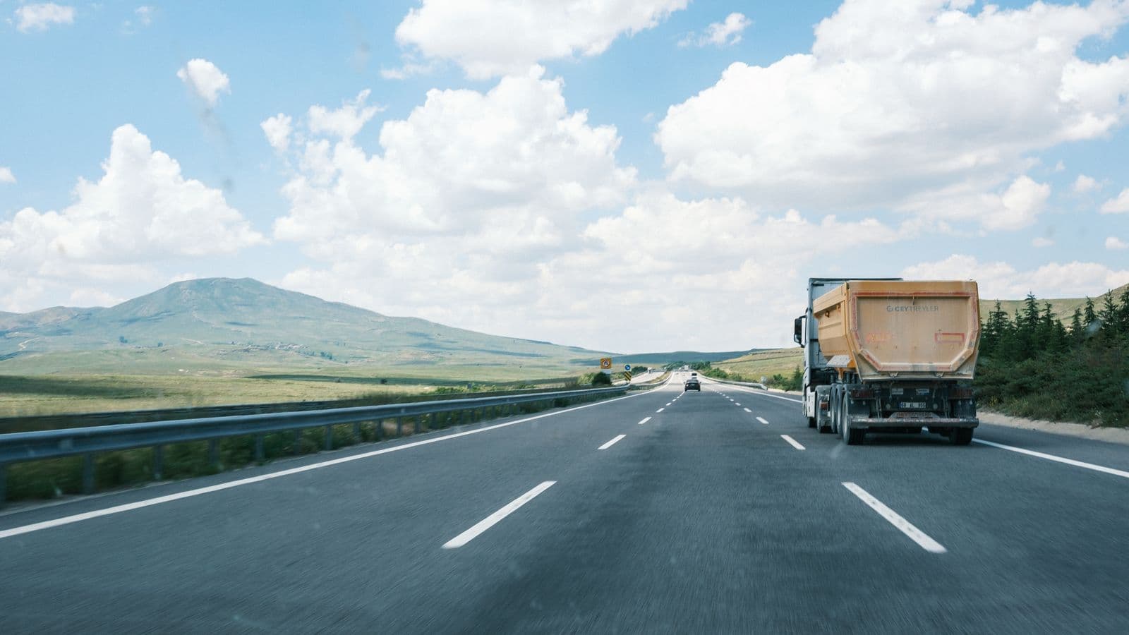 An GoGoX freight truck on an open inter-state highway under a clear sky.