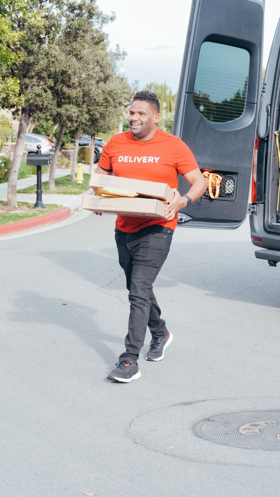 A GoGoX courier carrying stacked parcels from the back of a delivery van.